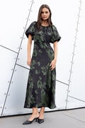 Woman wearing a green floral dress against a modern architectural background