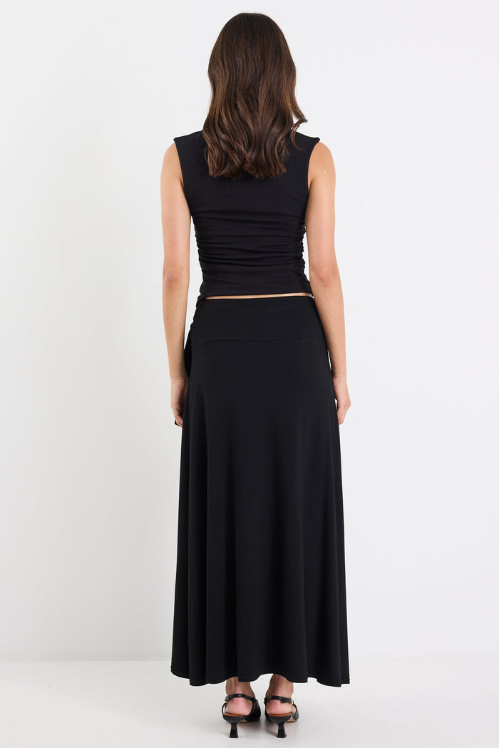 Woman wearing a black sleeveless top and long skirt on a white background
