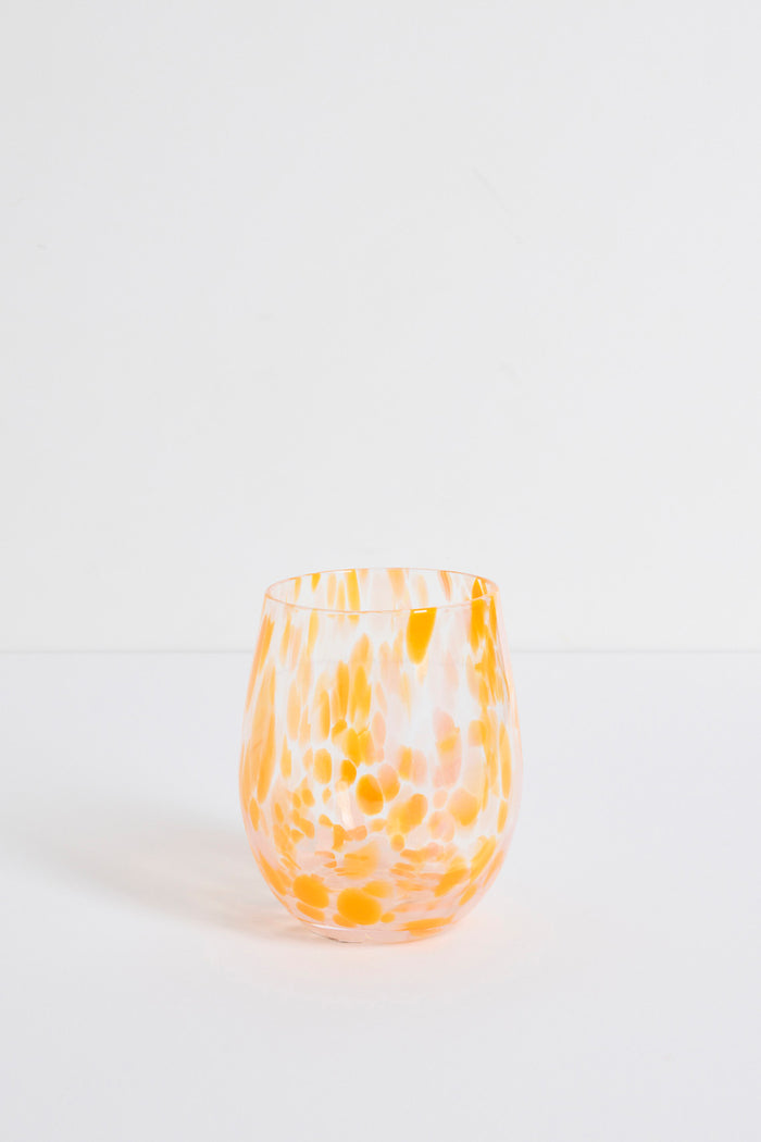 Stemless wine glass with orange and white marbled pattern on a light gray background