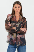Woman wearing a floral blouse with sheer overlay on a white background