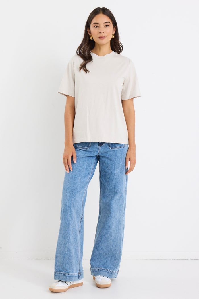 model wears a off white t-shirt with light blue jeans