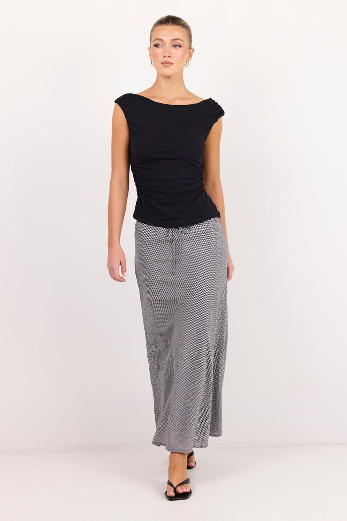 A woman modeling a black sleeveless top and a long gray skirt against a plain white studio background.