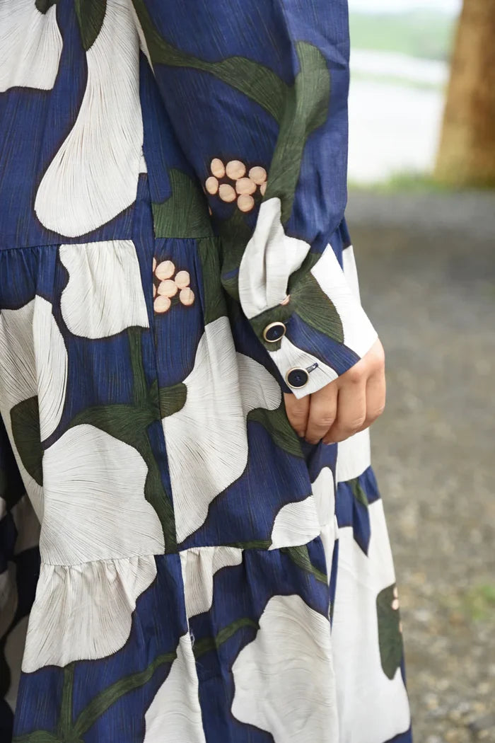 Close-up of a person wearing a patterned dress with blue, white, and green colors.