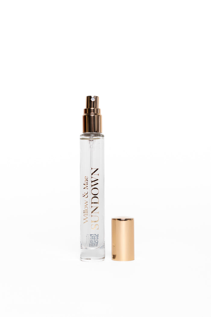 Small clear spray bottle with gold cap and text on a white background