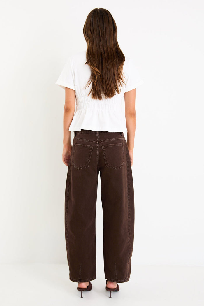 Person wearing brown wide-leg pants and a white top on a white background