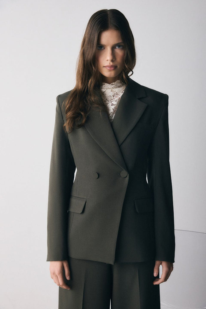 Woman wearing a dark green suit against a white background