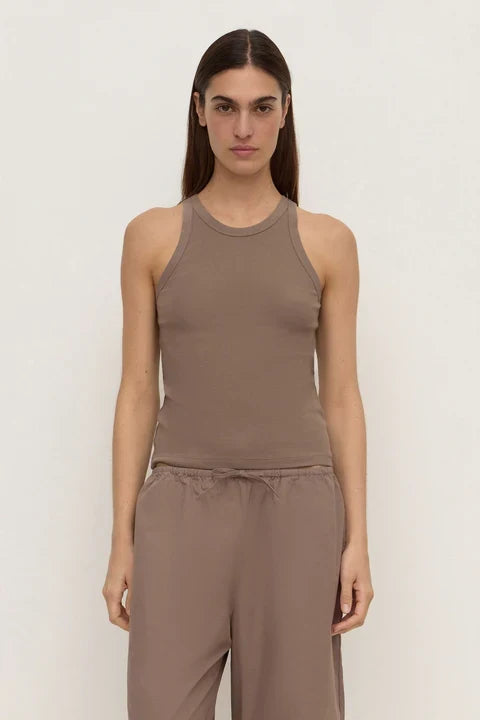A woman modeling a sleeveless ribbed tank top and matching drawstring pants in a taupe-brown color, set against a plain off-white studio background.