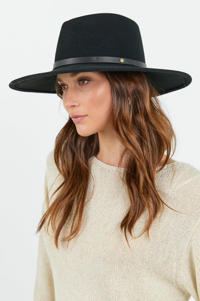 Woman wearing a black hat against a white background