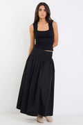Woman wearing a black sleeveless top and long black skirt on a white background