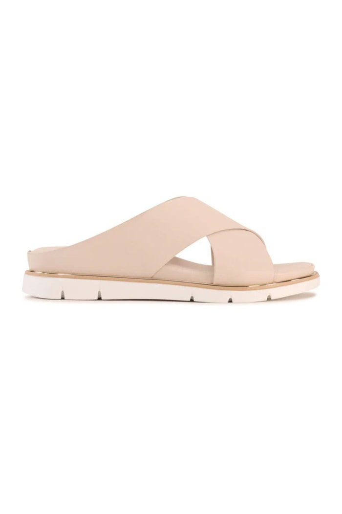 A single light beige leather slide sandal with crisscrossing straps and a low chunky sole, shown in profile against a plain white background.