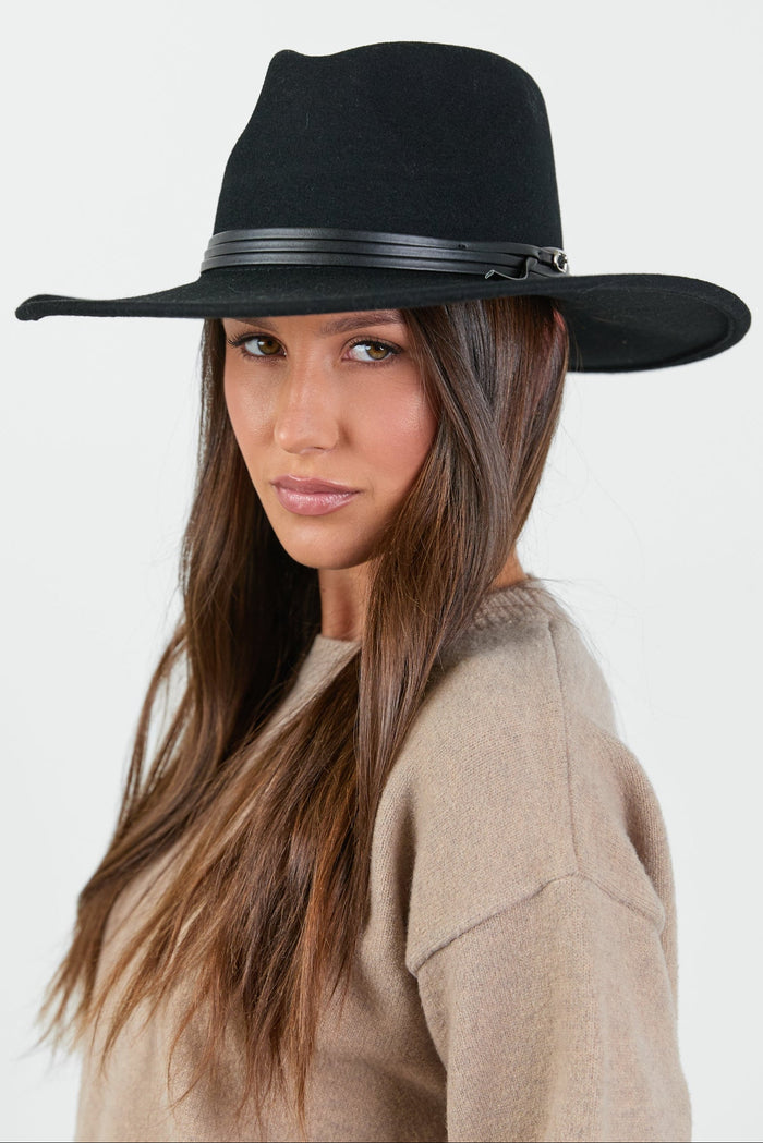 A stylish black Panama wool hat with a wide brim and a sleek black stacked trim band, set against a neutral background. The hat has a structured design and a minimalist aesthetic, adding an elegant touch to any outfit.