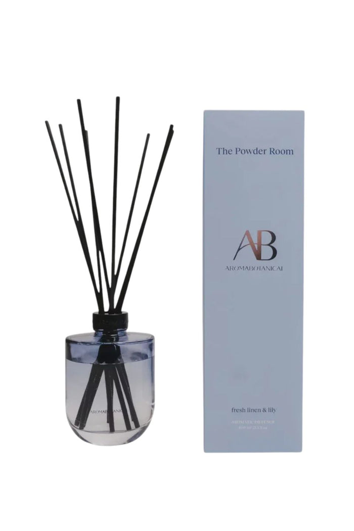 A reed diffuser bottle with black reeds next to its light blue packaging box. The box is branded 'The Powder Room' and 'AB All Purpose Room'.