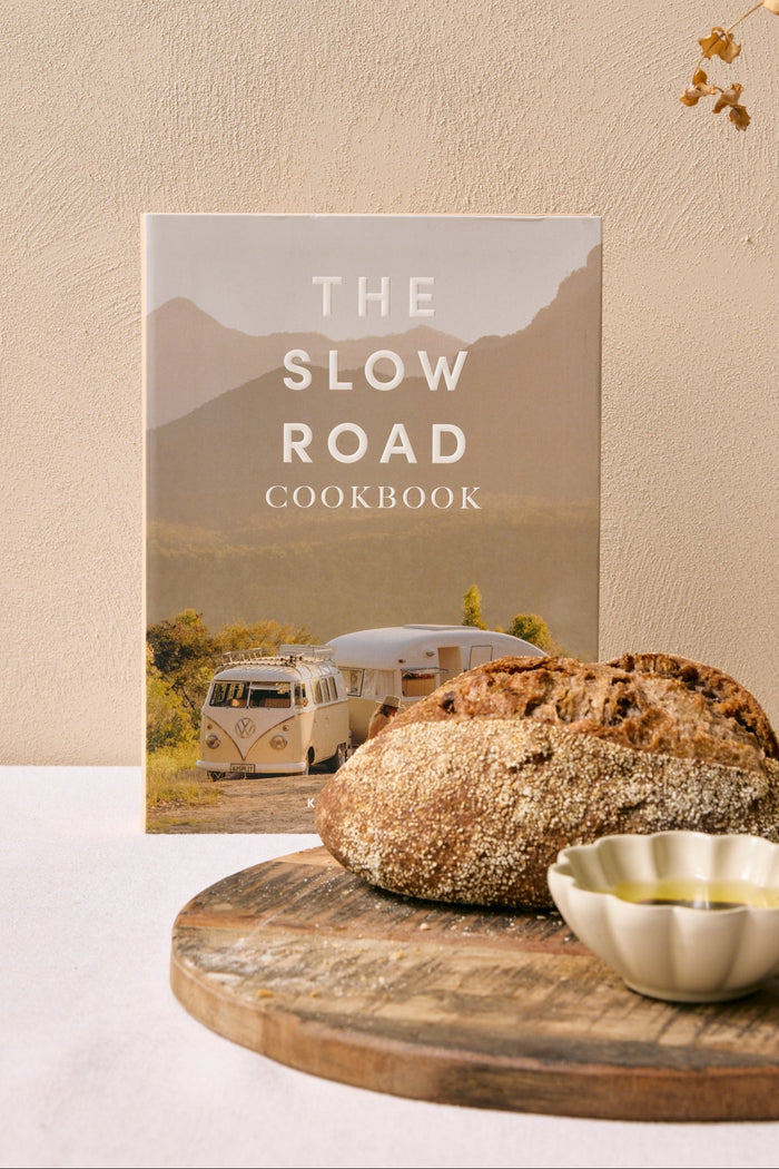 The Slow Road Cookbook on a table with bread and olives