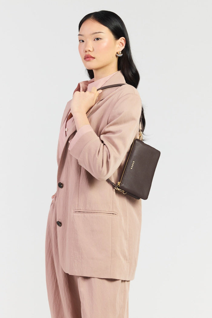 Woman wearing a pink suit with a matching handbag on a light gray background
