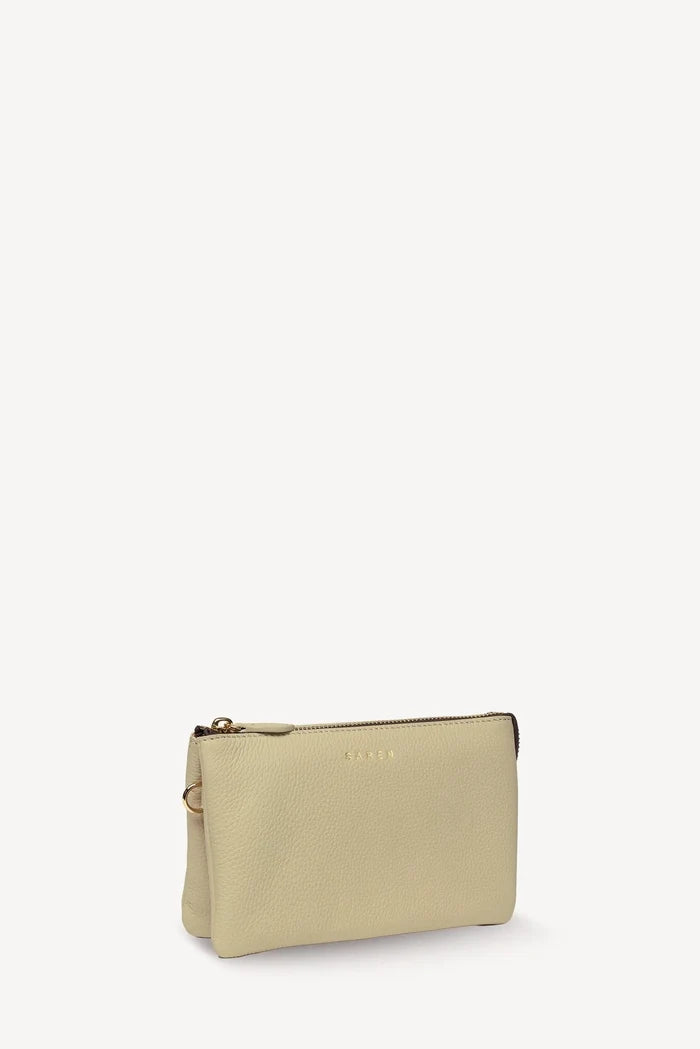 A small beige pebbled leather pouch with a gold-tone zipper and a debossed logo on the front, photographed on a clean white background.