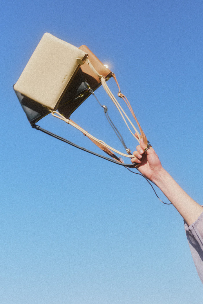 Hand holding bags against a clear blue sky