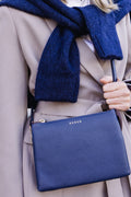 Person wearing a blue scarf and holding a blue handbag with a visible brand logo.