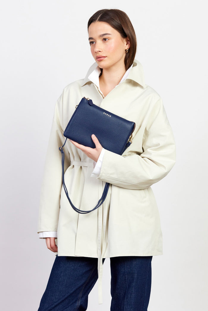 Woman holding a navy blue clutch bag against a white background
