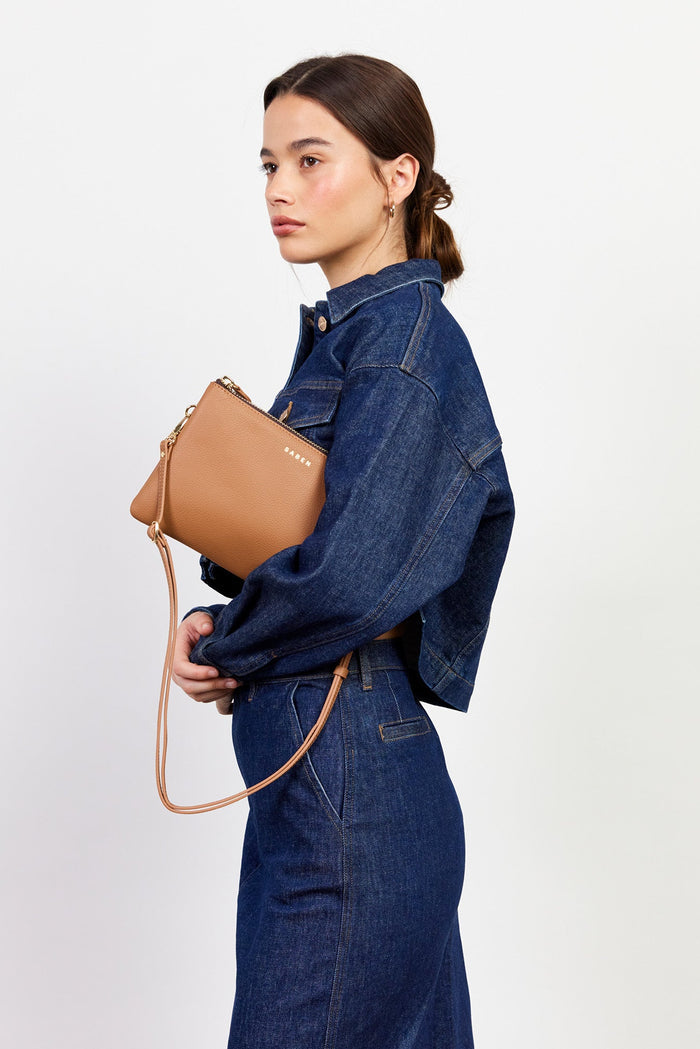 Woman holding a tan handbag against a white background