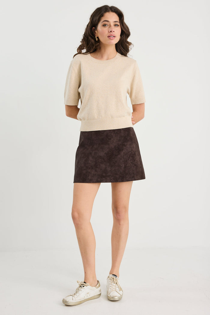 Woman wearing a beige sweater and dark skirt on a white background
col_pattern