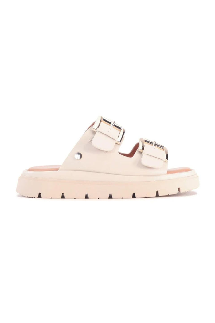 A single light beige double-strap slide sandal with metallic silver buckles and a chunky sole, shown from a side profile on a white background.