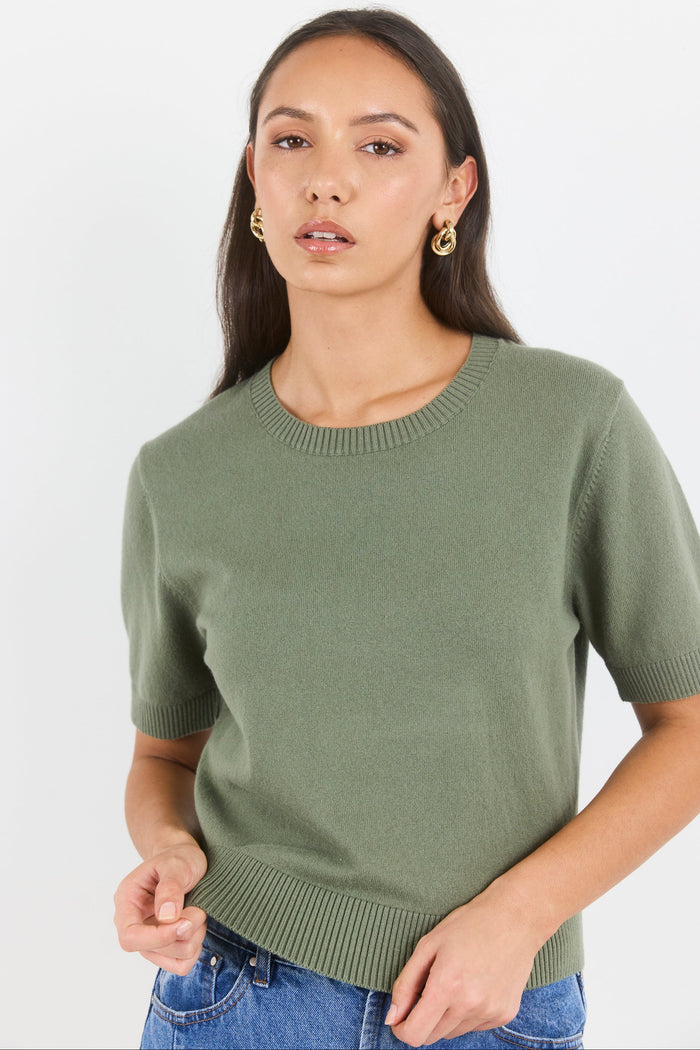Woman wearing a green sweater against a white background