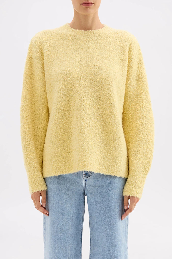 Person wearing a yellow sweater and light blue jeans on a white background