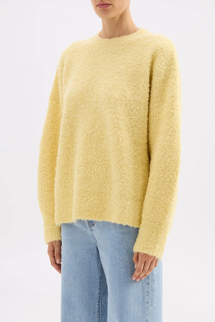 Person wearing a yellow sweater and light blue jeans on a white background