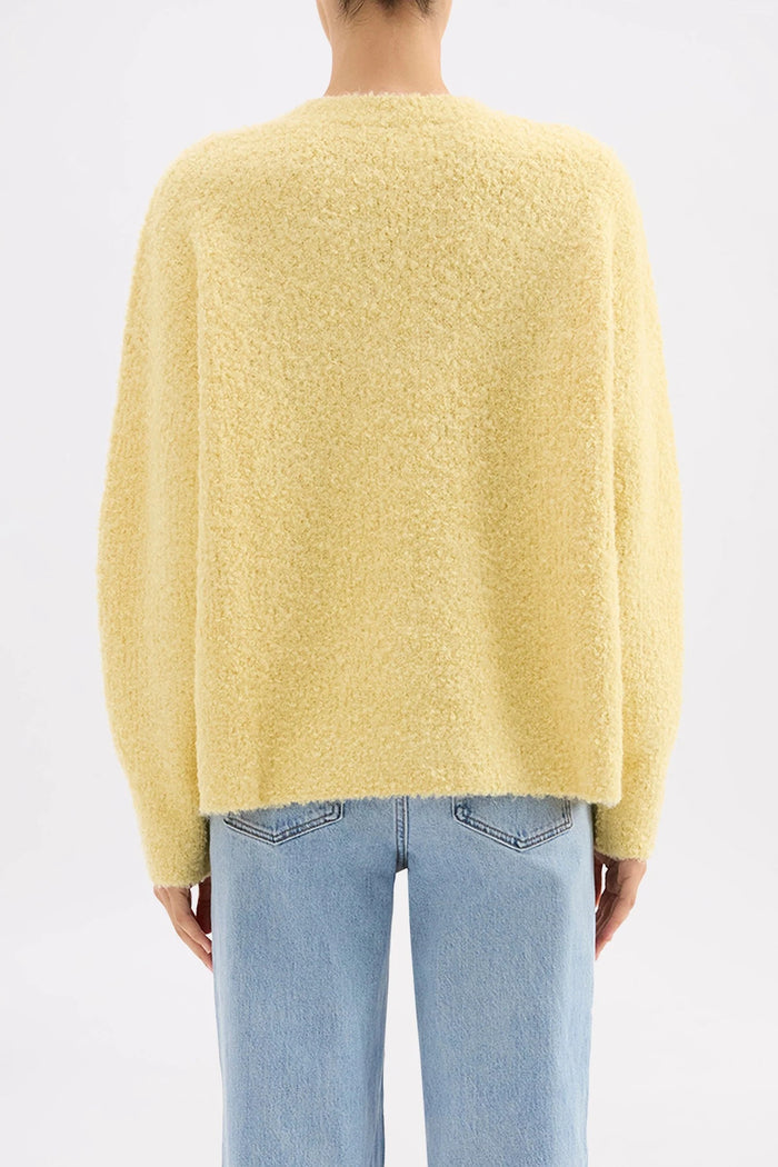 Person wearing a yellow sweater and light blue jeans on a white background