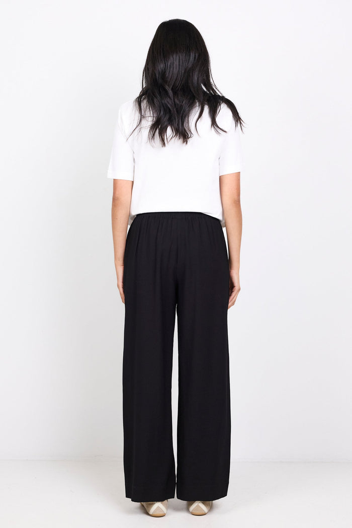 Person wearing a white top and black pants on a white background