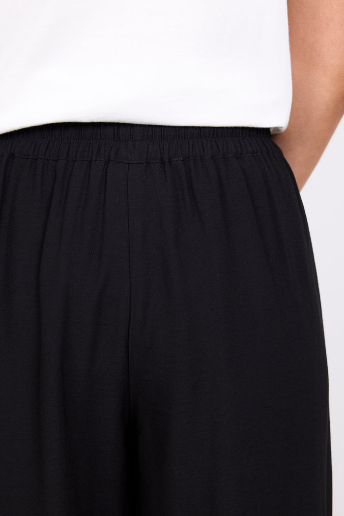 Black pants with a white top on a light gray background