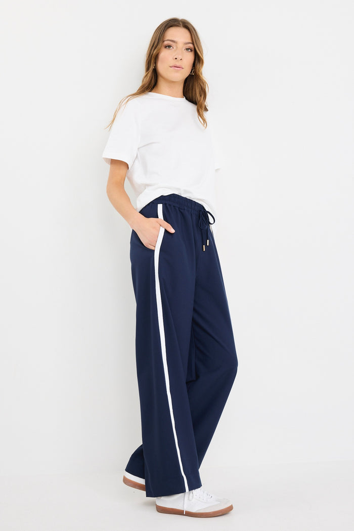 Woman wearing high-rise plain navy wide-leg pants with an elastic waistband and drawstring tie, styled with white sneakers and a white tee.