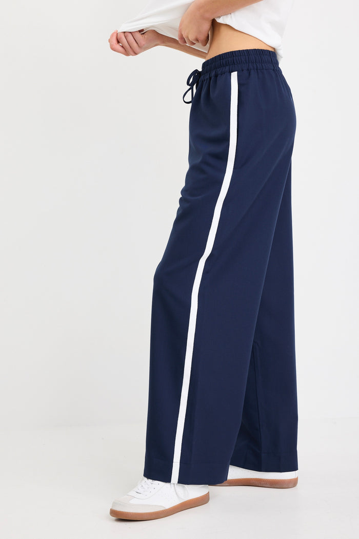 Woman wearing high-rise plain navy wide-leg pants with an elastic waistband and drawstring tie, styled with white sneakers and a white tee.