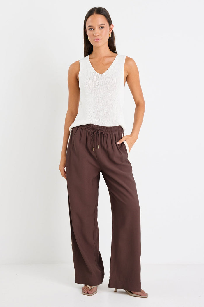 Woman wearing a white sleeveless top and brown wide-leg pants on a white background
col_pattern