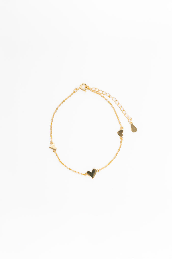 Gold bracelet with heart-shaped charms on a white background