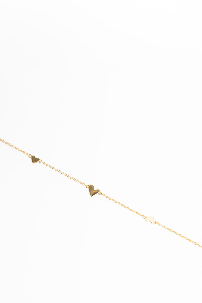 Gold anklet with heart-shaped charms on a white background
