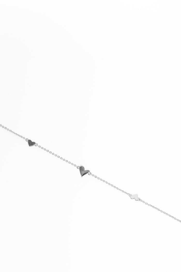 Silver bracelet with heart and triangle charms on a white background