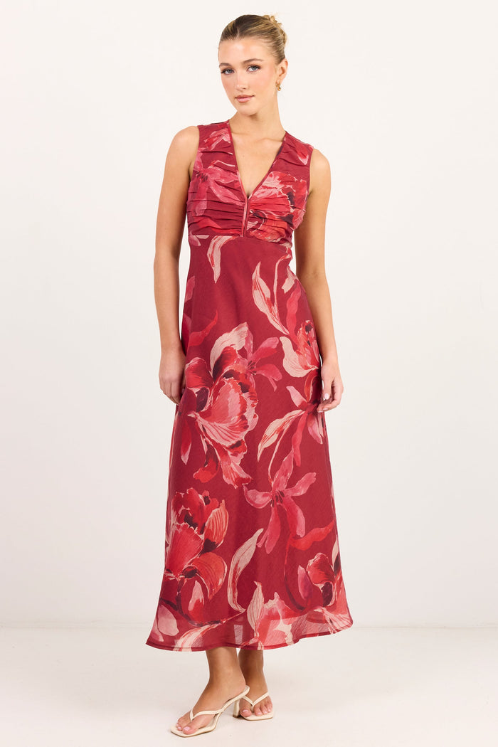 A woman modeling a sleeveless red maxi dress with a large pink and white floral print, standing against a plain white studio background.
col_pattern