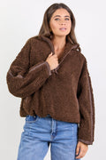 Woman wearing a brown fleece jacket and blue jeans on a white background