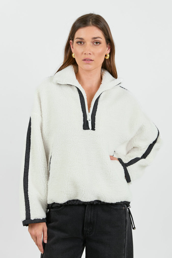 This cozy cream fleece jacket features a zip-up front, sporty black side stripes, and a relaxed fit, paired with black wash jeans for a casual yet stylish look.
