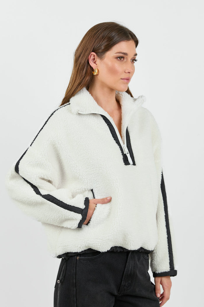 This cozy cream fleece jacket features a zip-up front, sporty black side stripes, and a relaxed fit, paired with black wash jeans for a casual yet stylish look.