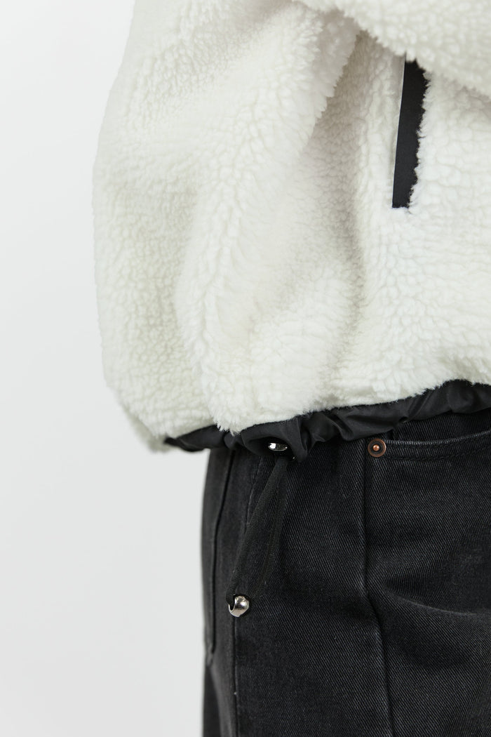 This cozy cream fleece jacket features a zip-up front, sporty black side stripes, and a relaxed fit, paired with black wash jeans for a casual yet stylish look.