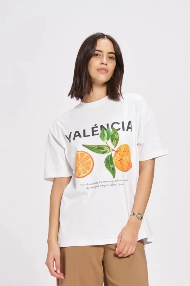 Person wearing a white t-shirt with 'Valencia' and orange graphics, paired with beige shorts on a white background.