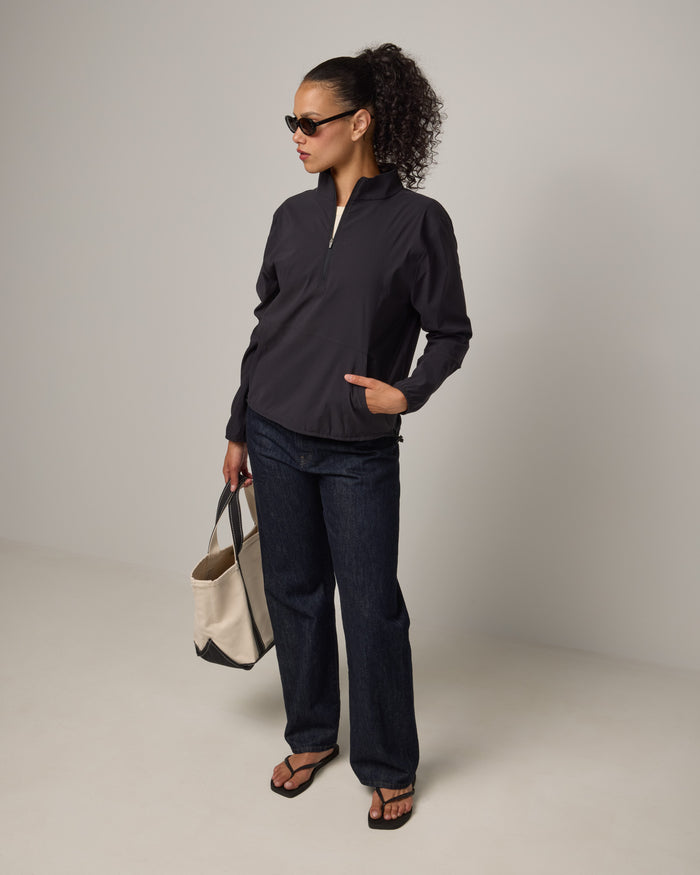 Model wearing Venus Quarter Zip in Black. Venus Quarter Zip is a merino wool lightweight long sleeve pullover with a front pocket available in sizes XS-XXL.