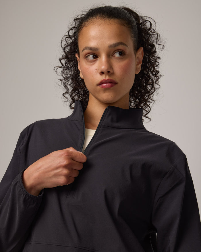 Model wearing Venus Quarter Zip in Black. Venus Quarter Zip is a merino wool lightweight long sleeve pullover with a front pocket available in sizes XS-XXL.