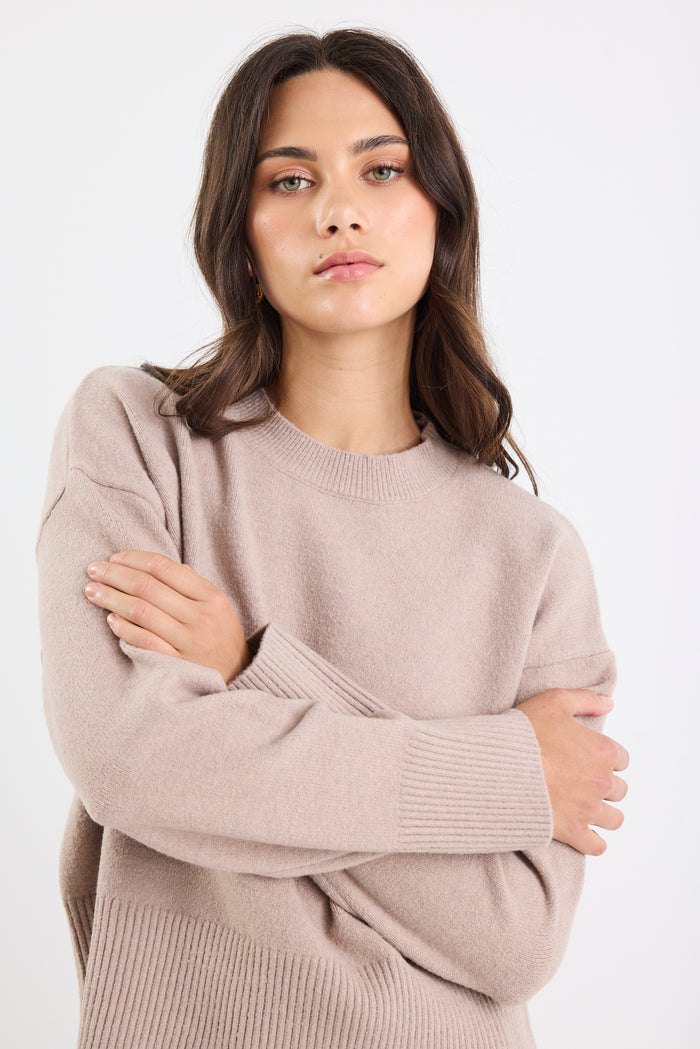Woman wearing a beige sweater against a white background