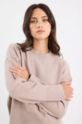 Woman wearing a beige sweater against a white background