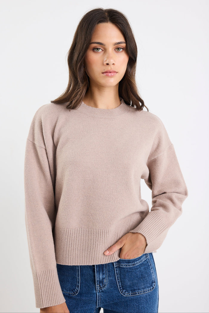 Woman wearing a beige sweater and blue jeans on a white background
col_pattern