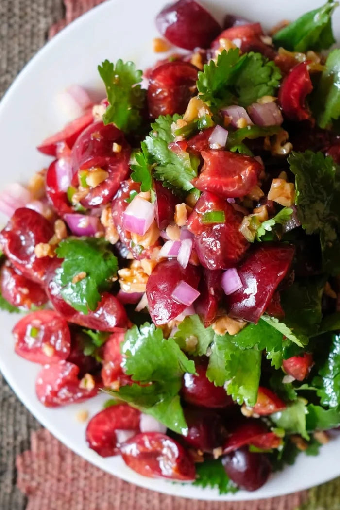 Salad with cherry tomatoes, green leaves, and red onions on a white plate.