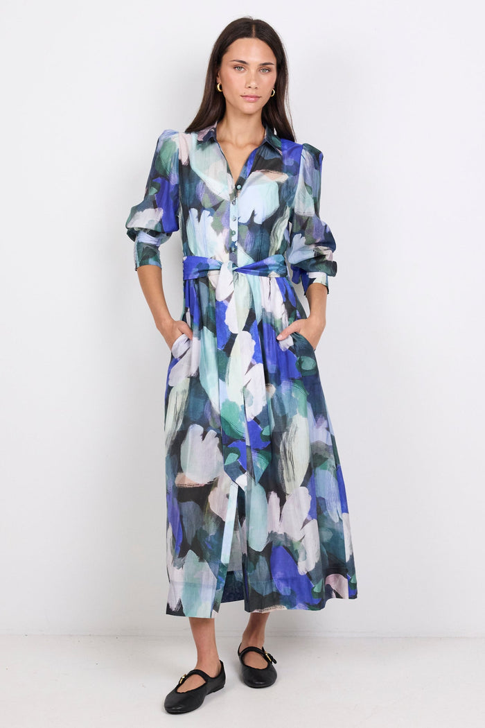 Woman wearing a long, blue patterned dress on a white background